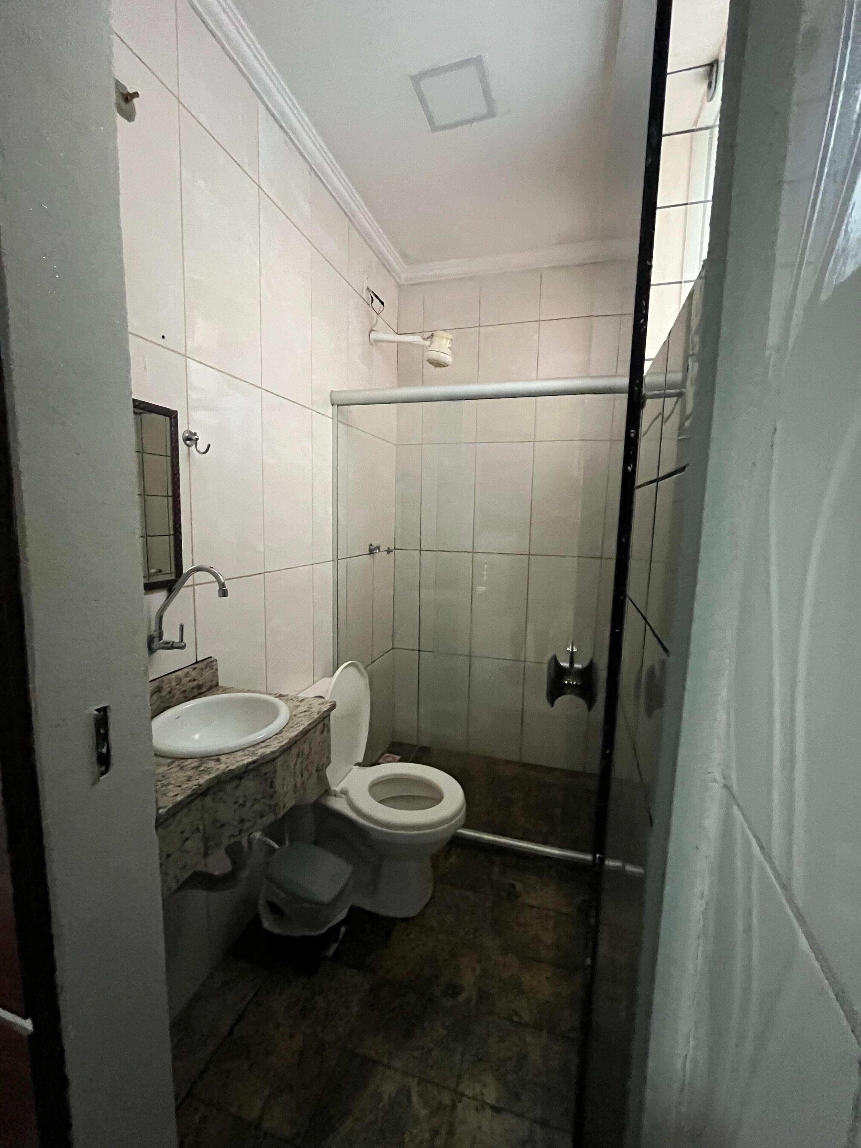 A small bathroom with a toilet, sink, and shower.