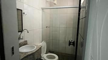 A small bathroom with a toilet, sink, and shower.