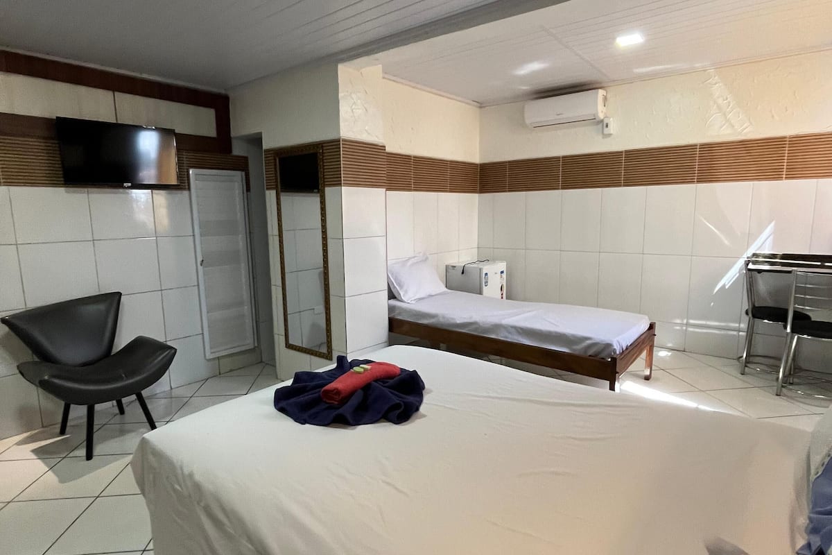 Une chambre d’hôtel avec un lit, une chaise, un bureau et un téléviseur.