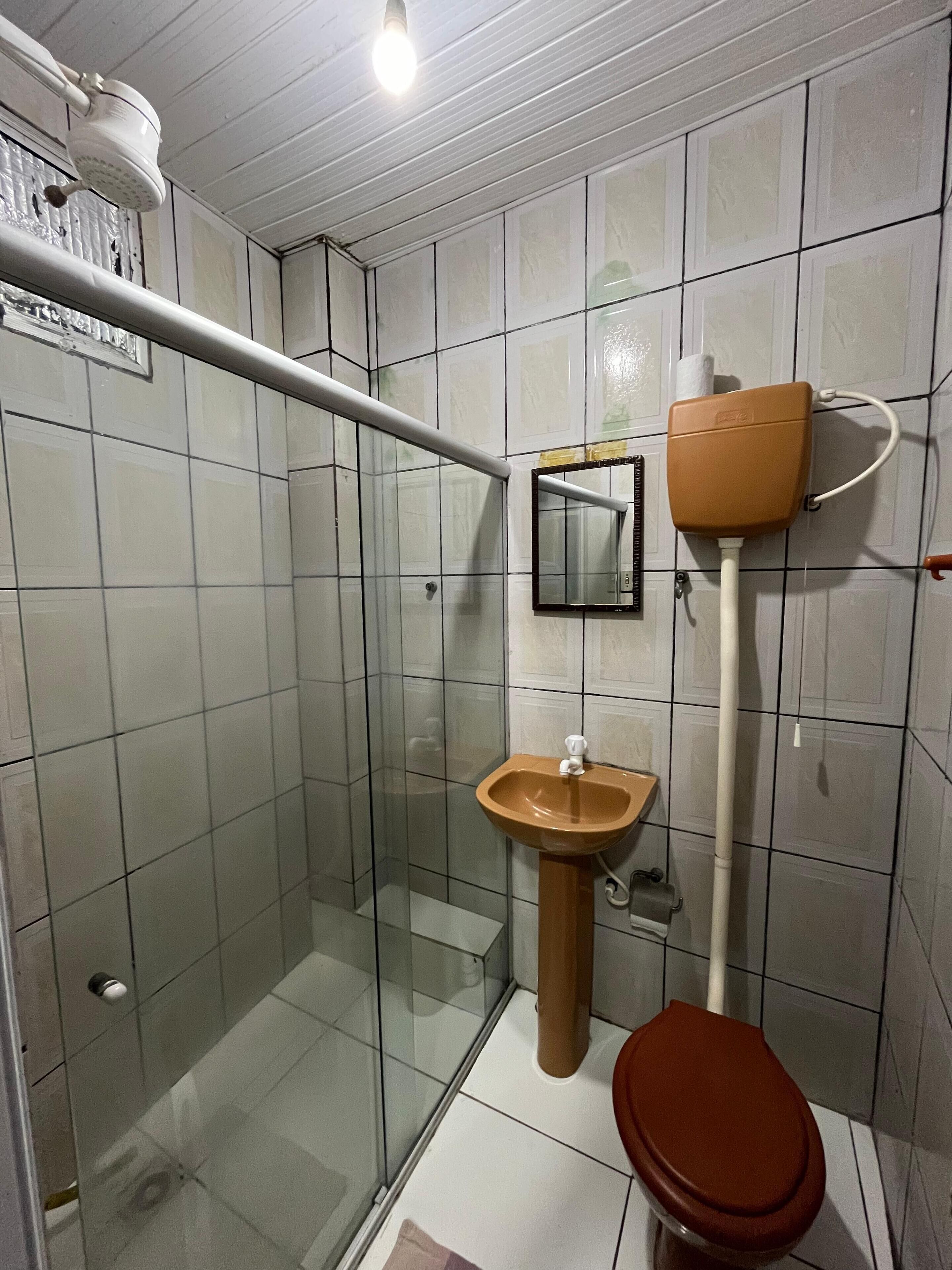 A small bathroom with a glass shower enclosure, a sink, and a toilet.