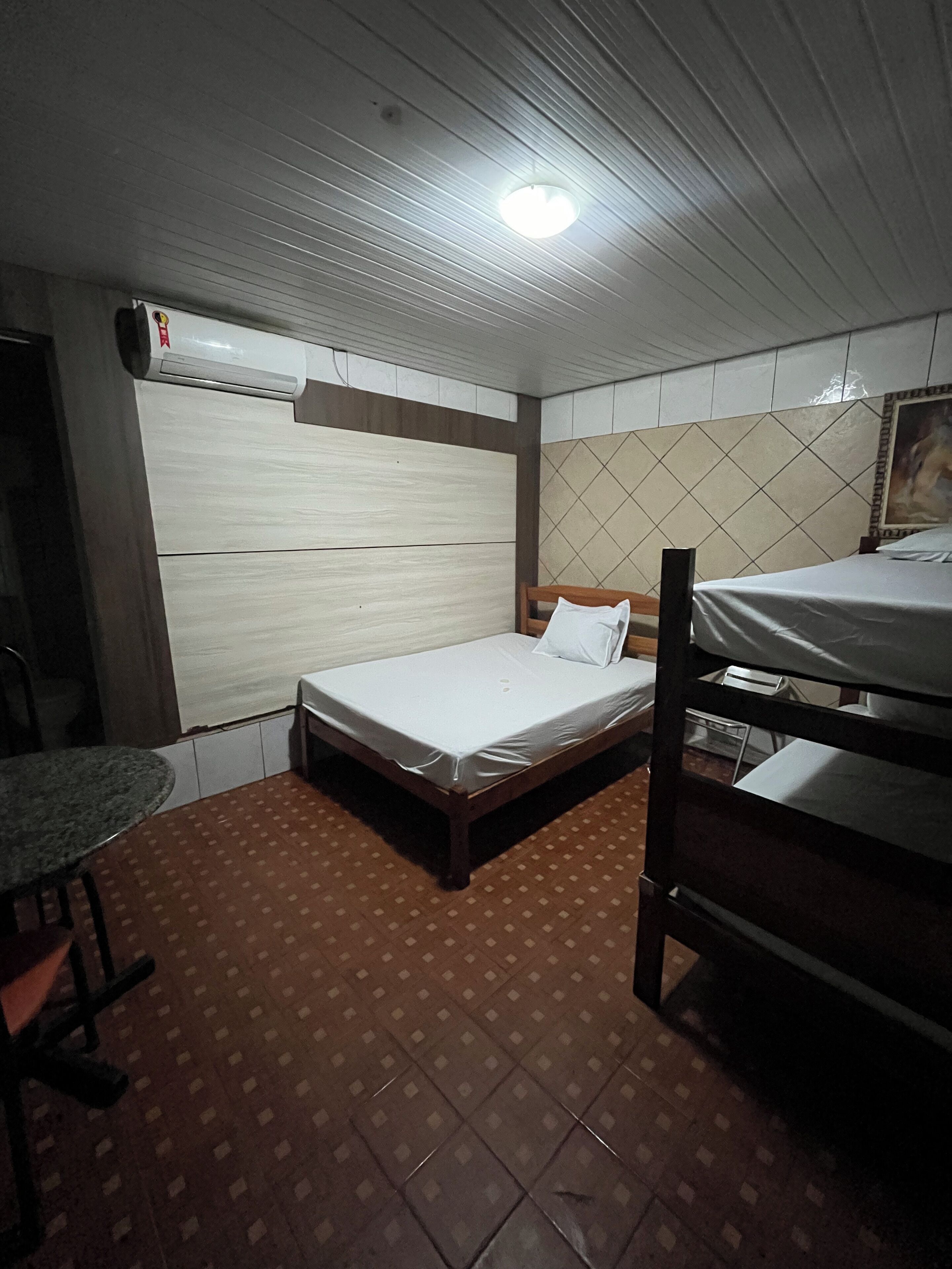 Una habitación pequeña y funcional con una cama individual, una mesa y una litera.