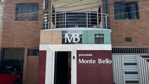Un edificio con un cartel que dice "pousada Monte Bello" y un balcón con barandilla.