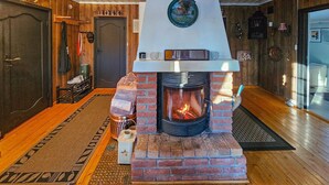 Una habitación acogedora con chimenea de ladrillo, piso de madera y una puerta con perchero.