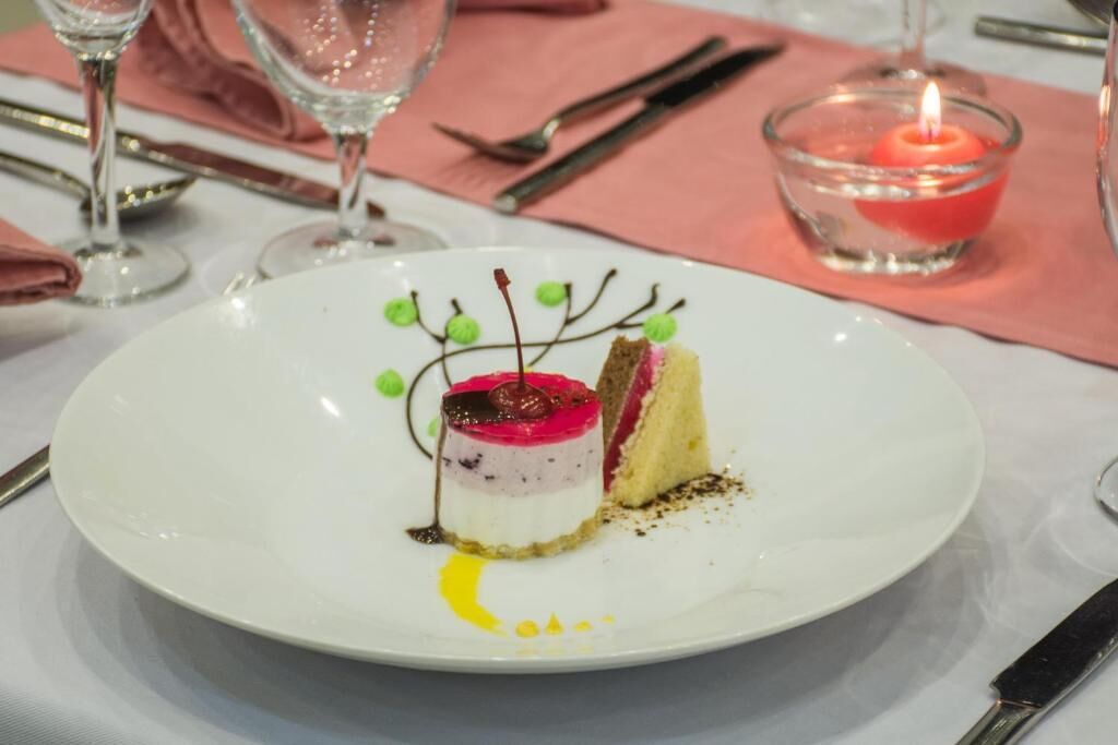 A dessert on a white plate with a candle in a glass holder nearby.