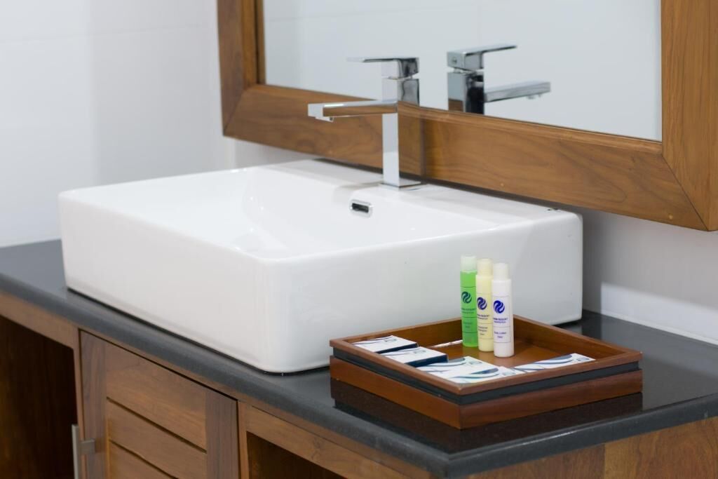 Une salle de bain avec un lavabo blanc, des meubles en bois et un miroir au-dessus du lavabo.