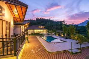 Ein modernes Haus mit Swimmingpool, überdachter Terrasse und Blick auf den umliegenden Wald.