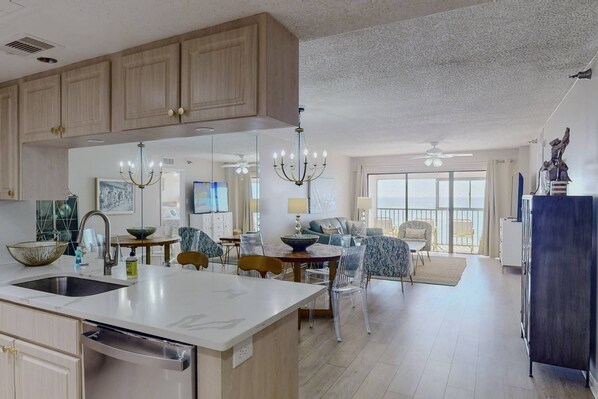 A spacious kitchen with a large island, wooden cabinets, and a dining area with a chandelier.