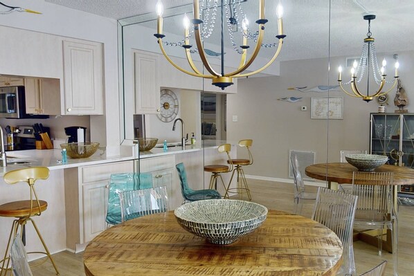 Una cocina moderna con armarios blancos, una isla central y un comedor con una mesa redonda de madera y sillas.