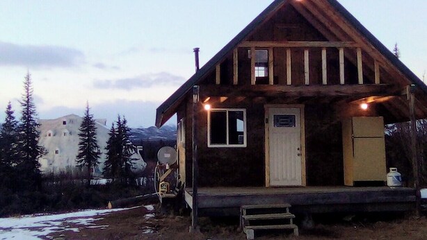 A wooden cabin with a pitched roof, a front door, and a small porch area. - Igloo City Cabin Rentals #1 Charming Cabin in Broad Pass at the Igloo Property (Cantwell)