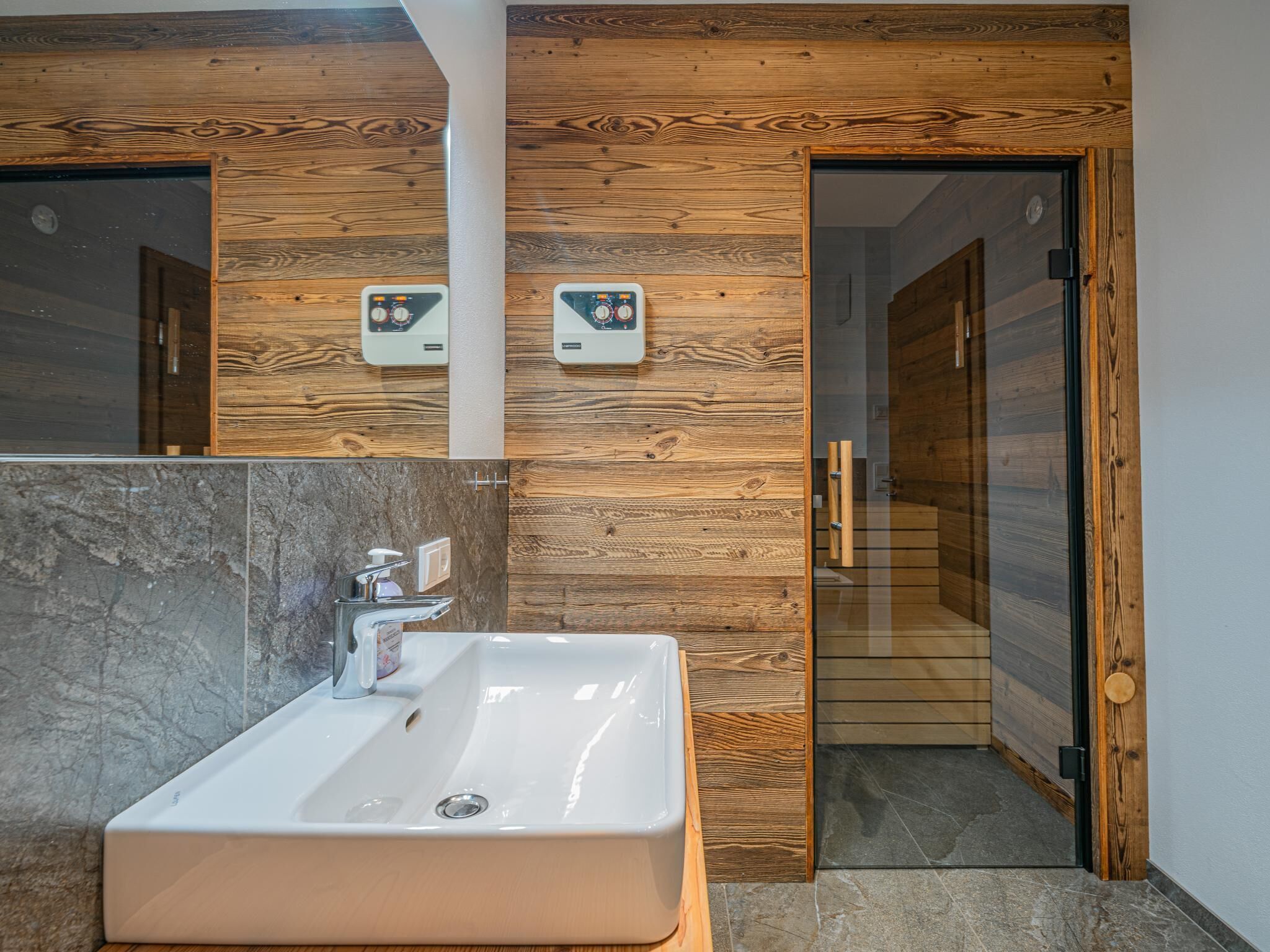 Ein Badezimmer mit einem großen Waschbecken, Holzvertäfelung und einem Spiegel.