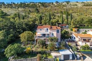 A hillside residential area with houses featuring balconies, stone walls, and terraced gardens. - Seaview House Apartments (Krsan)