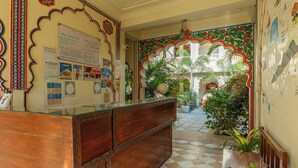 A reception area with a wooden counter, a bulletin board with travel tips, and a check-in desk. - Banana Hostel (Pushkar)