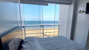 Ein Schlafzimmer mit einem großen Fenster mit Blick auf einen Strand.