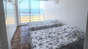 Ein Schlafzimmer mit zwei Betten, einem Fernseher und Meerblick.