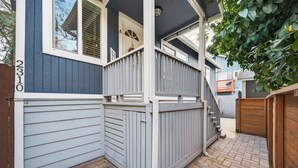Propiedad residencial con fachada azul, una puerta blanca y un camino de ladrillo.