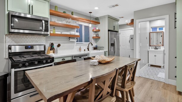 Una cocina moderna con electrodomésticos de acero inoxidable, estantes de madera y una isla central.