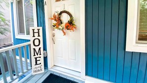 Puerta principal con un adorno de lazos y un cartel que dice "HOME sweet HOME".