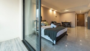 Een moderne slaapkamer met een glazen deur naar een badkamer, een eethoek en een keuken.