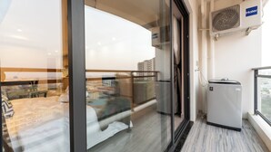 Een moderne hotelkamer met een glazen scheidingswand, een bed, een kleine verwarming en uitzicht op de stad.