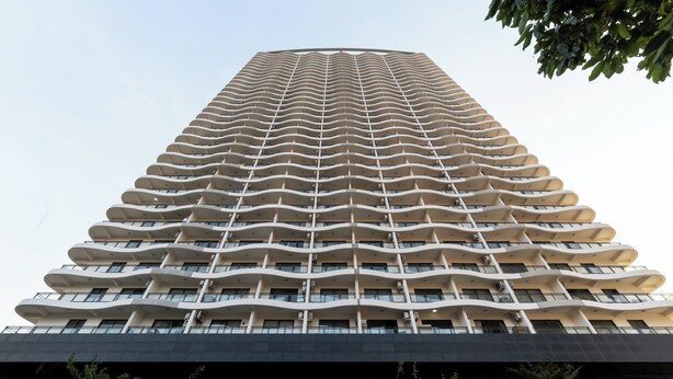 Een hoog, modern gebouw met een unieke, golvende gevel en meerdere balkons.