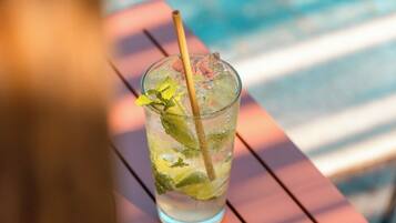 A glass of iced drink with mint leaves and a straw on a wooden table.