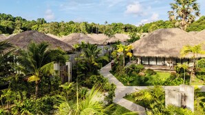 A resort with thatched-roof huts, a central pathway, and lush tropical vegetation. - JATI Koh Russey (Prey Nob)