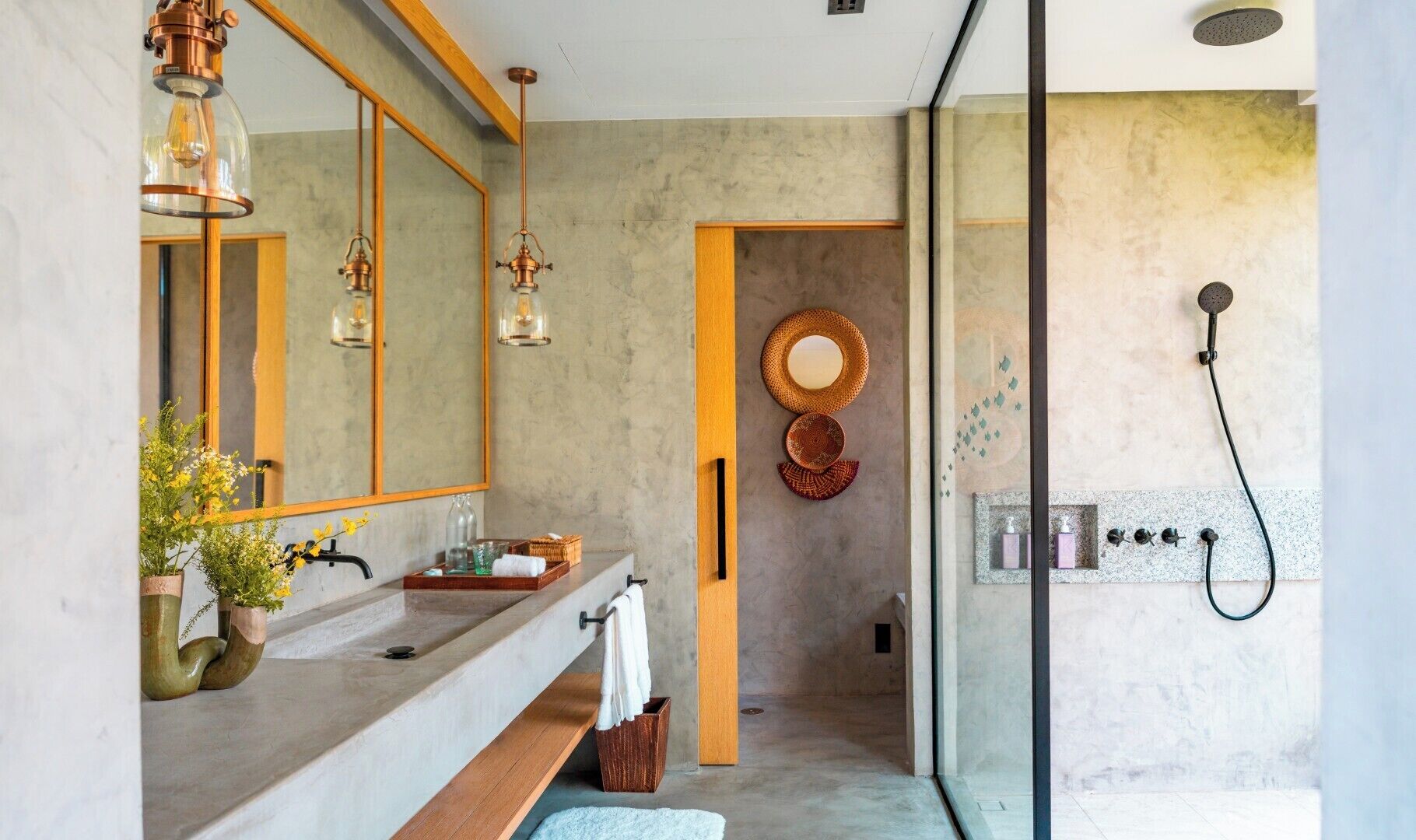 Un baño moderno con un espejo grande, dos lámparas colgantes, una ducha y un tocador con lavabo y toallero.
