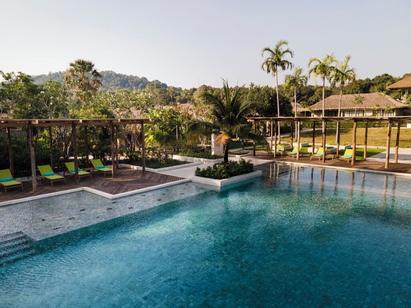 A pool area with lounge chairs and a wooden pergola.