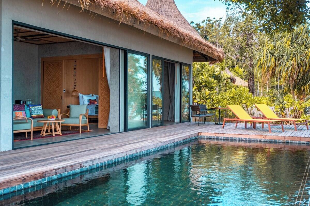 Uma villa moderna com piscina, deck de madeira e área de estar ao ar livre.
