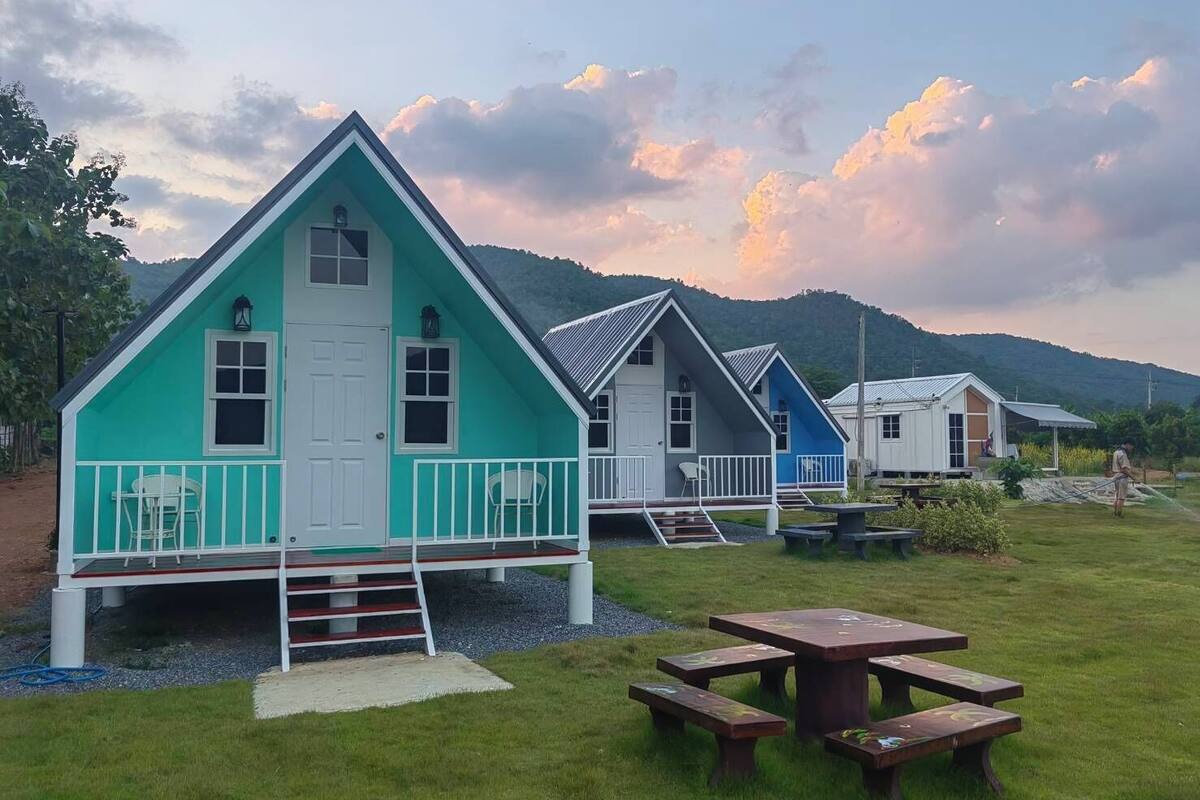 A row of small, colorful cabins with a grassy lawn and picnic tables in front.