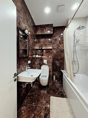A modern bathroom with a bathtub, a shower, and a toilet.