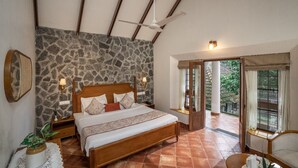 A bedroom with a stone wall, a wooden bed, a ceiling fan, and a view of the outdoors. - HOTEL TREETOP (Peermade)