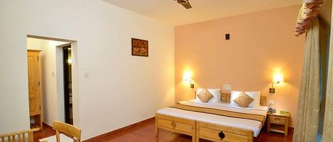 Un dormitorio con cama, mesitas de noche, ventilador de techo y ventana con cortinas.