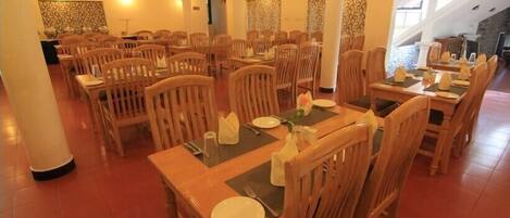 A restaurant with multiple wooden tables and chairs, arranged in a spacious layout.