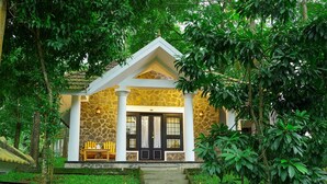 A small stone building with a porch, steps leading up to the entrance, and a bench outside. - HOTEL TREETOP (Peermade)