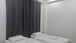 A room with two single beds, each with a white mattress and pillow, and a small table with a book on it. - GO INN Night Bazaar Chiang Mai (Chiang Mai)