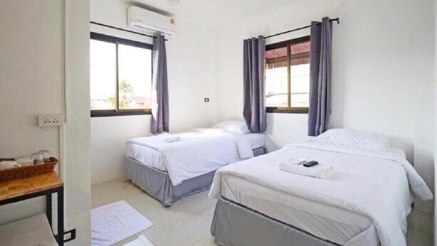 A room with two single beds, a desk with a chair, an air conditioning unit, and a window with curtains. - GO INN Night Bazaar Chiang Mai (Chiang Mai)