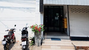 A building with two air conditioning units, a closed shop, and two motorcycles parked in front. - GO INN Night Bazaar Chiang Mai (Chiang Mai)
