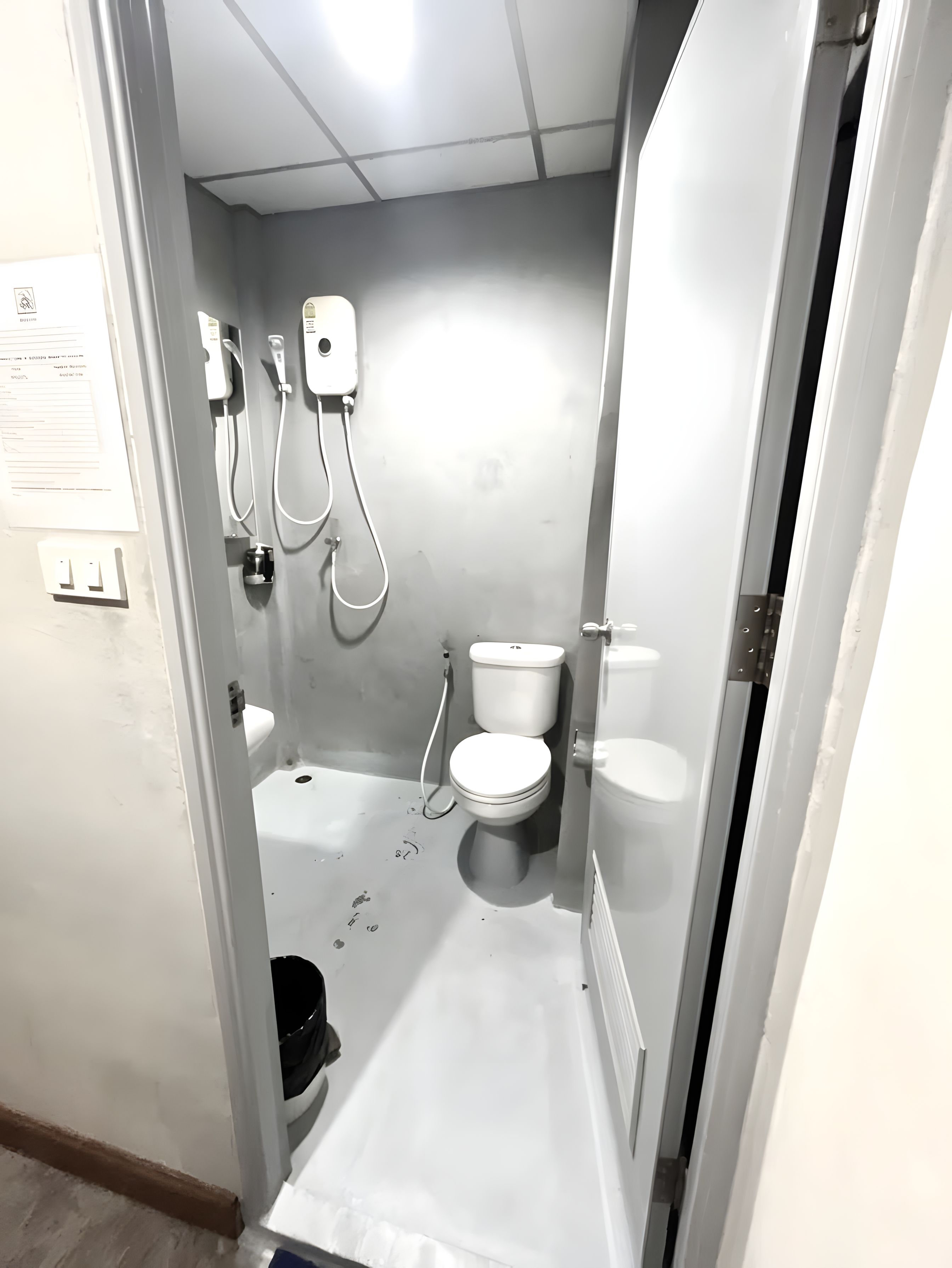 A small, narrow bathroom with a toilet, bidet, and shower unit.