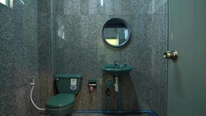 Un baño pequeño y cerrado con inodoro, lavamanos y espejo.