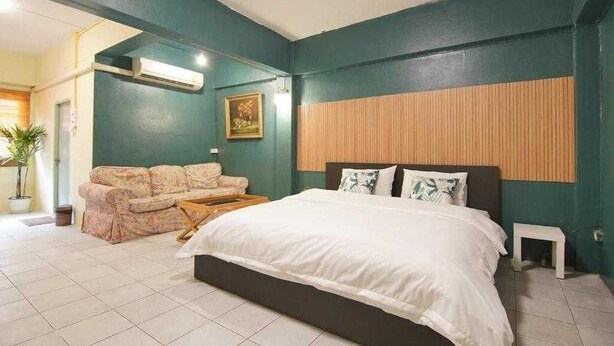 Un dormitorio con cama, sofá y cabecera de madera.