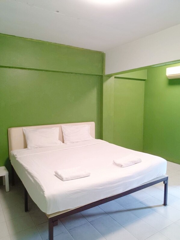 A neatly made bed with white linens and pillows in a room with green walls and a white ceiling. - GO INN The Grand Palace (Bangkok)