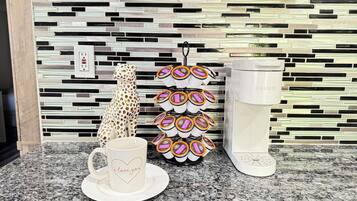 A kitchen counter with a coffee maker, a mug with a heart design, and a mug holder with multiple cups.