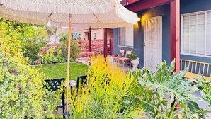 Een binnentuin met een kleurrijk zonnescherm, een houten bankje en diverse planten.