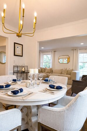A round dining table set for six with white tablecloths, blue napkins, and candles. - BBQ • Swingset • Pets OK • Family Retreat (Charlotte)
