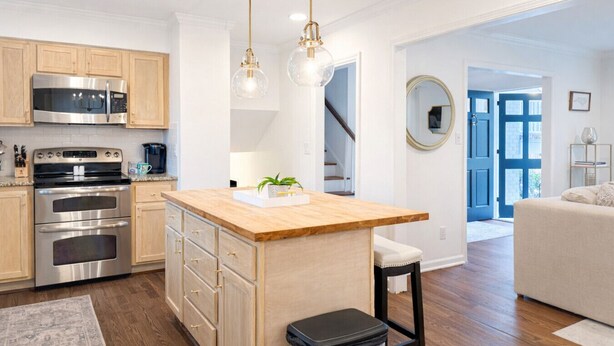 A modern kitchen with stainless steel appliances, wooden cabinets, and a central island. - BBQ • Swingset • Pets OK • Family Retreat (Charlotte)