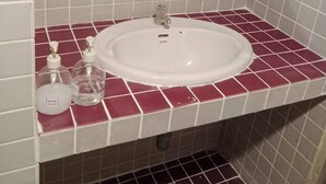 A bathroom with a white sink, a mirror, and two soap dispensers on a red-tiled countertop. - GO INN Maya Chiang Mai (Chiang Mai)