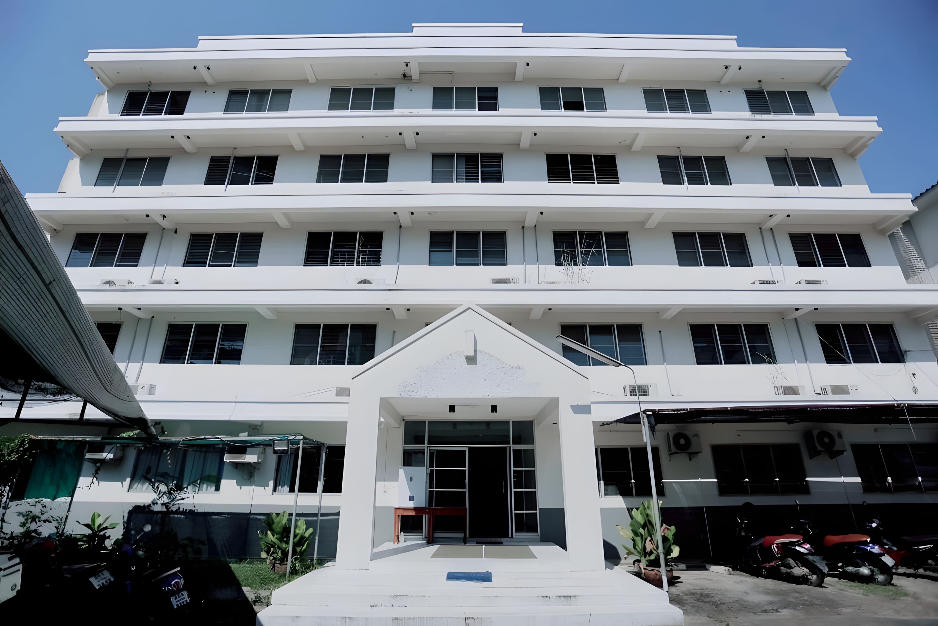 A multi-story building with a central entrance, large windows, and a flat roof.
