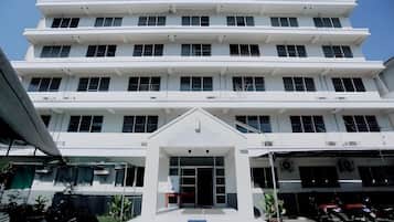 Un edificio de varios pisos con una entrada central, ventanas amplias y techo plano.