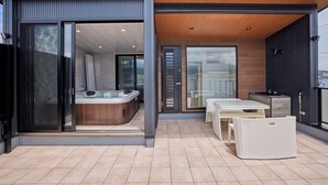 Un patio exterior moderno con un jacuzzi, una mesa y sillas.